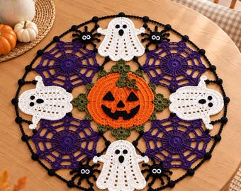 May include: A round crochet doily featuring a central orange jack-o'-lantern surrounded by four white ghosts, four purple spider webs, and small black spiders. The design is bordered by a black crocheted edge with small black spheres along the perimeter.