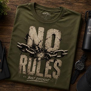 May include: An olive green t-shirt featuring a graphic of cracked stone letters spelling NO RULES with a metal chain wrapped around the center. Below the text, the words BUILT DIFFERENT are printed in white. The shirt has a crew neck collar.