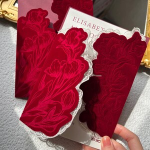 May include: Close-up of red velvet cards with a floral design and white lace trim. The cards have a tulip pattern embossed on the front. The word "ELISABETH" is visible on the card inside.