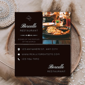 May include: A rectangular business card for Borcelle Restaurant with a dark brown background. The left side features a logo, the name, and the text Dishes of the Peoples of the World. The right side shows a photo of a meal. Contact details are below.