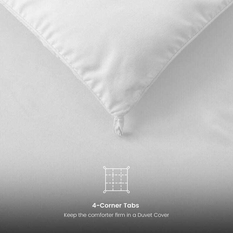 Op de afbeelding: Close-up van een witte dekbedhoek met een vastgeknoopte hoeklip. De afbeelding bevat de tekst "4-Corner Tabs" en "Keep the comforter firm in a Duvet Cover". Het dekbed staat op een witte achtergrond.