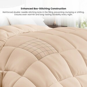 Op de afbeelding: Een close-up van een beige dekbed met een box-stitch ontwerp. Het dekbed heeft een rasterachtig stikselpatroon. De tekst "Enhanced Box-Stitching Construction" is zichtbaar.