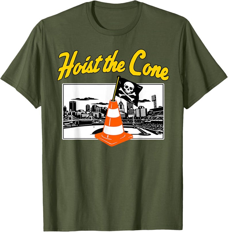 May include: Olive green t-shirt with the text "Hoist the Cone" in yellow. The graphic features a traffic cone with a skull and crossbones flag in front of a city skyline.
