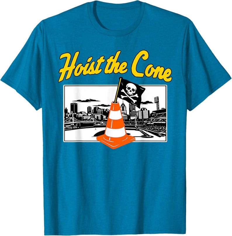 May include: A turquoise t-shirt with a graphic that says "Hoist the Cone" in yellow text. The graphic features a pirate flag on a traffic cone in front of a city skyline.