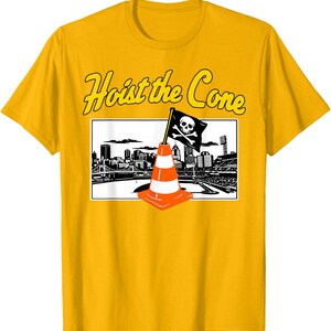 May include: A yellow t-shirt featuring a graphic with the text "Hoist the Cone." The graphic includes a black and white cityscape, an orange and white traffic cone, and a pirate flag with a skull and crossbones.