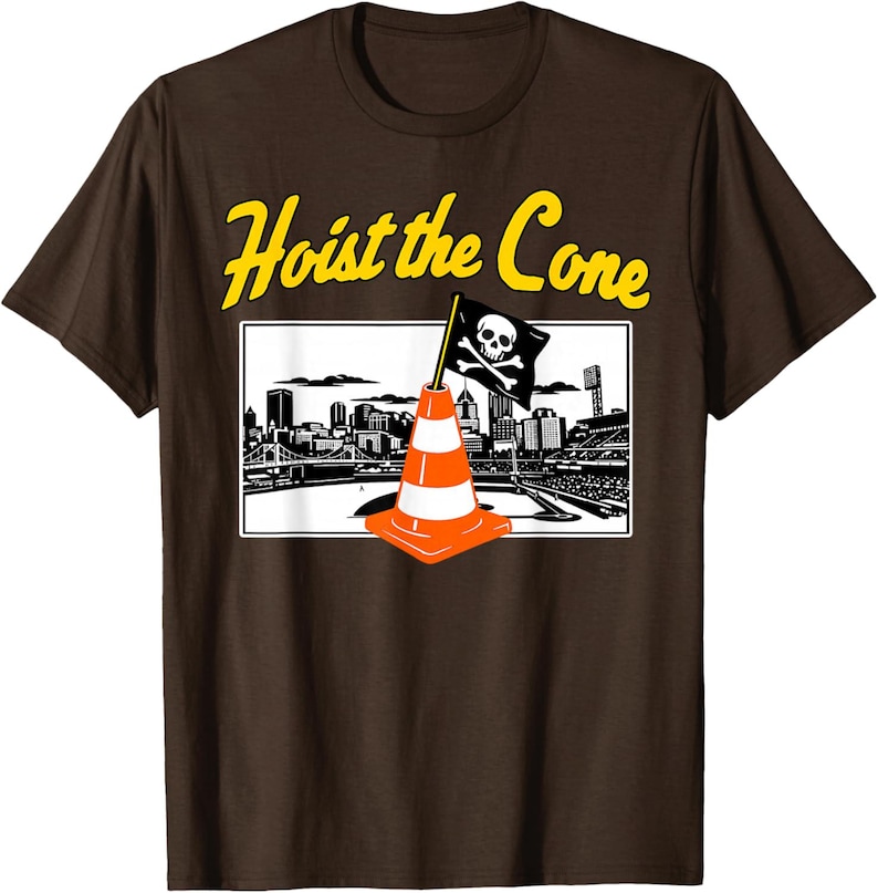 May include: Brown t-shirt with a graphic featuring a traffic cone with a skull and crossbones flag in front of a city skyline. The text "Hoist the Cone" is in yellow.