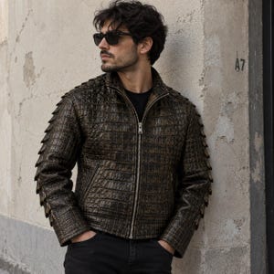 May include: A dark brown, textured jacket with a crocodile-skin pattern, featuring a full-length silver front zip, a high collar, and distinctive pointed, scale-like protrusions running down the outer length of each sleeve.