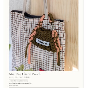 Op de afbeelding: Een gehaakte mini-tasbedel in olijfgroen en perzik, bevestigd aan een totebag met een rasterpatroon. De tas heeft de tekst "MIWACO." De afbeelding is een digitaal downloadpatroon voor beginners tot gevorderden.