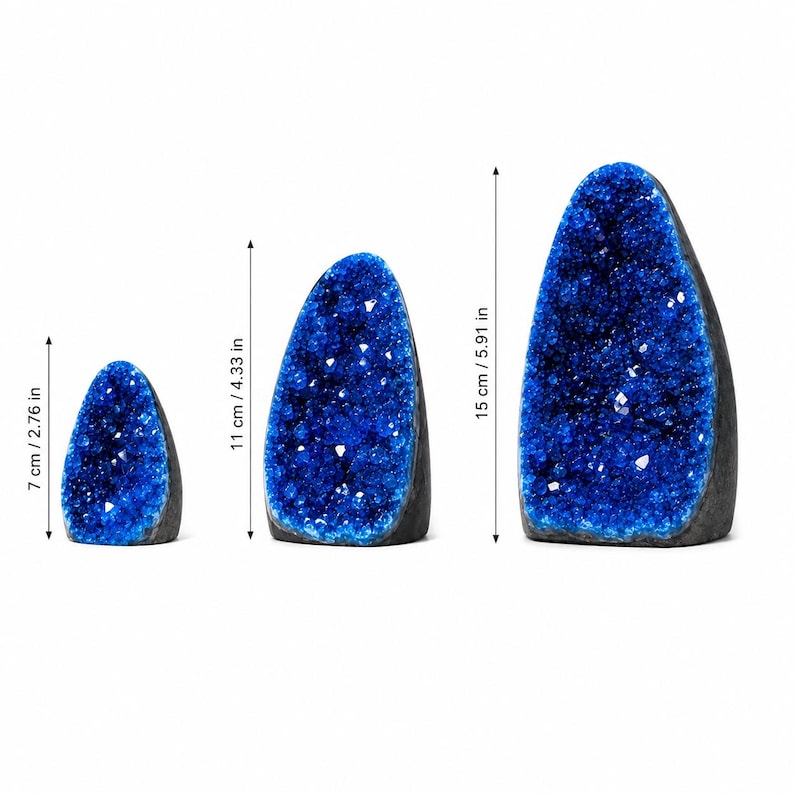May include: Three blue geode specimens with dark outer shells and crystalline interiors. The heights are indicated by arrows as 7 cm / 2.76 in, 11 cm / 4.33 in, and 15 cm / 5.91 in, showing a graduated size range for these decorative mineral formations.
