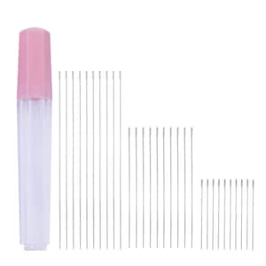 May include: A set of silver sewing needles arranged in three distinct height groups, accompanied by a clear plastic storage tube featuring a solid light pink cap. The needles are thin, metallic, and straight, displayed in a vertical orientation.