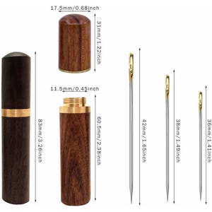 May include: A dark wood needle case with a brass band and a matching screw-top lid, shown with three silver sewing needles with gold-colored eyes. Dimensions are labeled as 3.26 inches total height, 1.22 inches lid height, and 2.38 inches base height.