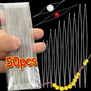 May include: A set of 50pcs collapsible eye beading needles made of thin, flexible silver metal wire. The needles are stored in a clear plastic sleeve. Several needles are shown outside the sleeve, with some threaded with yellow beads.