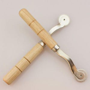 May include: Two sewing tracing wheels with light-colored wooden handles and silver-toned metal shafts. Each tool features a small, circular, serrated metal wheel at the end, designed for marking fabric patterns with precision and ease.