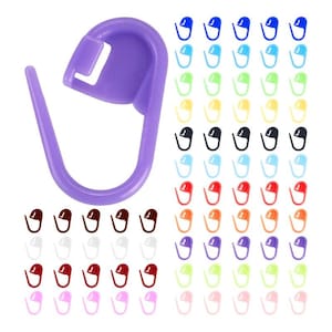 May include: A large purple plastic stitch marker shown in detail alongside a collection of many smaller stitch markers in various colors including blue, green, yellow, black, light blue, red, orange, purple, light green, white, maroon, and pink.