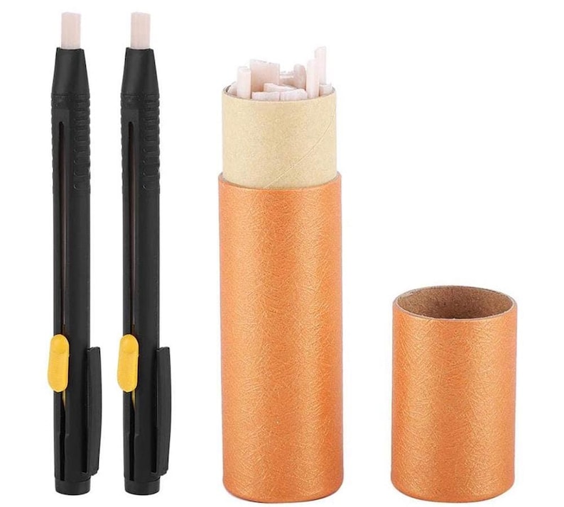 May include: Two black mechanical erasers with yellow accents and a cylindrical orange container filled with eraser refills. The container is open, revealing the pink eraser pieces. A separate orange tube is also shown.