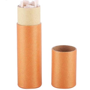 May include: An orange cylindrical container with a tan interior, partially open, revealing small, white, rectangular objects. The container is made of textured paper and has a matching lid.