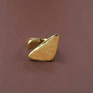 Handgjord abstrakt geometrisk ring i guld, bred oregelbunden triangulär platt topp, öppen bypass-rem.