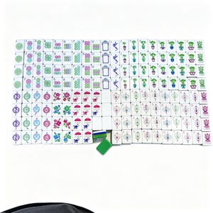 May include: A complete set of white rectangular mahjong tiles arranged in a grid. The tiles feature colorful illustrations of flowers, birds, monkeys, lanterns, bamboo, and numerical characters. Two loose green and blue tiles are placed below the grid.