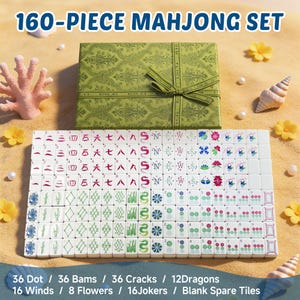 May include: A 160-piece Mahjong set featuring a green patterned storage box with a ribbon and white tiles with colorful symbols, including dots, bams, cracks, dragons, winds, flowers, and jokers, arranged in rows on a sandy surface.