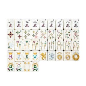 Op de afbeelding: Een set witte rechthoekige mahjongtegels met diverse kleurrijke ontwerpen, waaronder de cijfers &eacute;&eacute;n tot en met negen, sterpatronen, sceptericonen, kronen met de letters N, S, E, W, leeuwfiguren, jokertekst en bloemmotieven met strikken.
