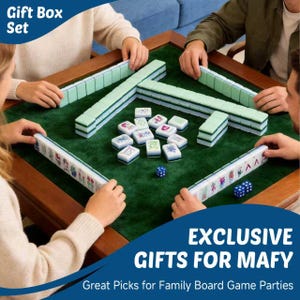 May include: A Mahjong game set featuring light green tiles with various colorful symbols and characters arranged on a dark green felt surface. The set includes multiple rows of tiles, individual playing tiles, and two blue dice for gameplay.