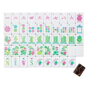 May include: A set of white mahjong tiles featuring colorful illustrations of numbers, bamboo, lotus flowers, pagodas, and birds. The tiles include directional markers labeled N, E, W, S, the word Joker, and Crak and Bam labels. One tile has a brown tortoiseshell pattern.