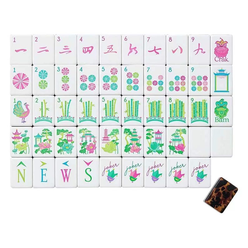 May include: A set of white mahjong tiles featuring colorful illustrations of numbers, bamboo, lotus flowers, pagodas, and birds. The tiles include directional markers labeled N, E, W, S, the word Joker, and Crak and Bam labels. One tile has a brown tortoiseshell pattern.