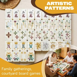 Op de afbeelding: Een set witte rechthoekige mahjongtegels met kleurrijke illustraties van cijfers, symbolen, kronen, leeuwen en het woord Joker. De tegels zijn in een raster gerangschikt en tonen diverse ontwerpen, waaronder bloemmotieven en sierlijke iconen.