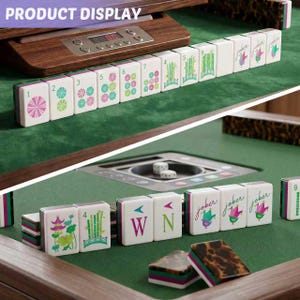 May include: A mahjong set featuring white tiles with colorful floral, bamboo, and joker designs, alongside lettered tiles. The set includes a wooden electronic display unit with buttons and a digital screen, all arranged on a green felt surface.