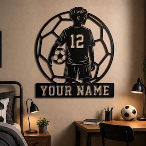 Könnte beinhalten: Schwarze Metall-Wandkunst mit einem Fußballspieler. Die Silhouette zeigt einen Spieler mit einem Fußball, vor einem Fußball-Design. Der Text "YOUR NAME" befindet sich darunter. Der Spieler trägt die Nummer 12 auf seinem Trikot.
