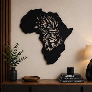 Peut inclure: Décoration murale en métal noir représentant le continent africain avec une tête de lion détaillée. La crinière et les traits du visage du lion sont finement sculptés. L'œuvre est fixée sur un mur clair, créant un contraste saisissant.
