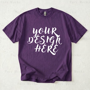 May include: A purple t-shirt with the text "YOUR DESIGN HERE" in white script. The shirt is a solid color and has a crew neck.