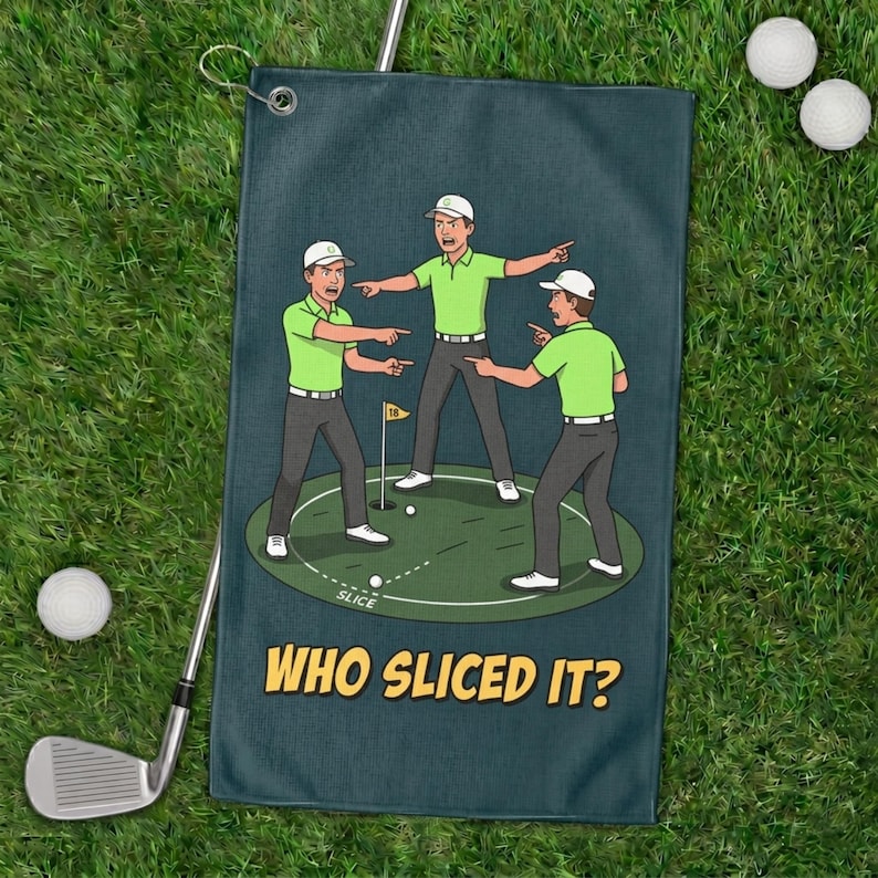 May include: A dark green golf towel featuring a graphic of three identical figures in lime green shirts and grey pants pointing at each other on a golf green. The text "WHO SLICED IT?" is printed in yellow below the illustration of the golfers.