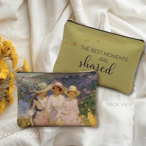 Puede incluir: Dos estuches con cremallera. Uno es de color verde oliva con el texto "THE BEST MOMENTS ARE shared". El otro estuche tiene una pintura de mujeres con vestidos y sombreros blancos. Flores amarillas en el fondo.