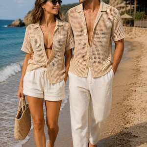 May include: Two beige crochet short-sleeve button-down shirts with a grid pattern. One shirt is paired with white drawstring shorts and a woven straw tote bag. The other shirt is paired with white trousers and brown leather slide sandals.