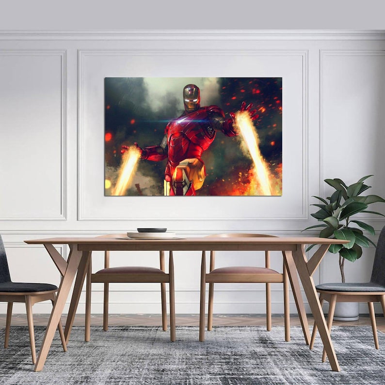May include: A framed canvas print featuring Iron Man in a dynamic pose, with energy beams emanating from his hands. The artwork showcases a red and gold armored figure against a backdrop of fire and smoke, creating a dramatic effect. The print is displayed above a wooden dining table.