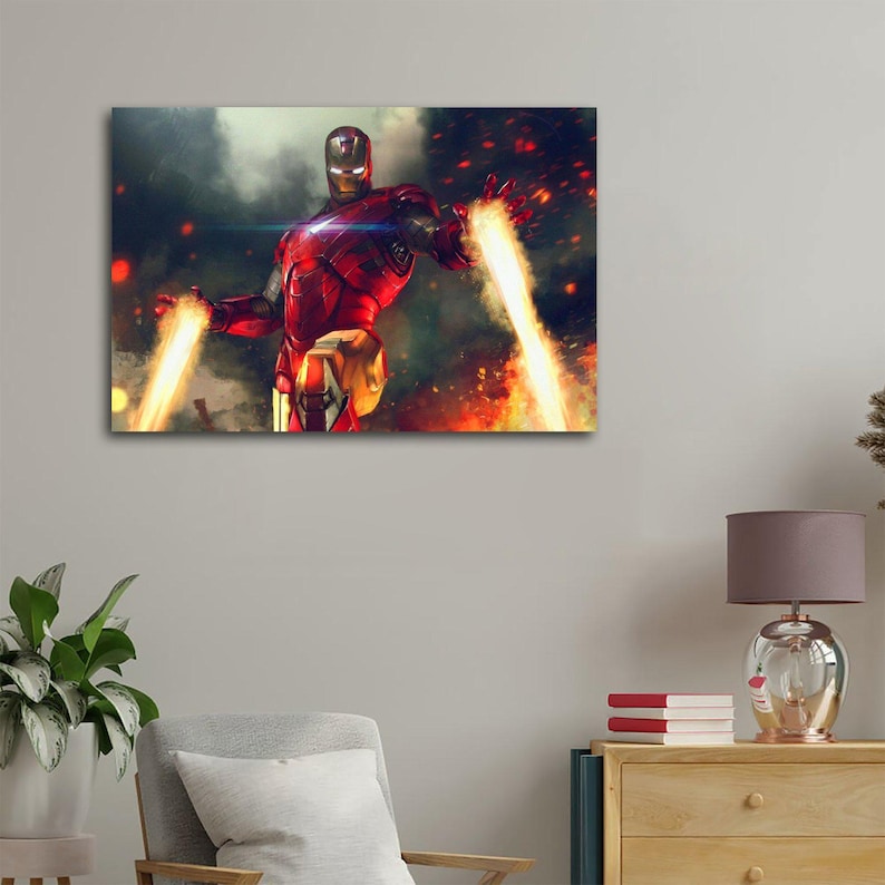 May include: A canvas print featuring Iron Man in a dynamic pose, with his hands emitting bright yellow energy beams. The artwork showcases the character in his iconic red and gold armor against a backdrop of fiery explosions and smoky clouds.