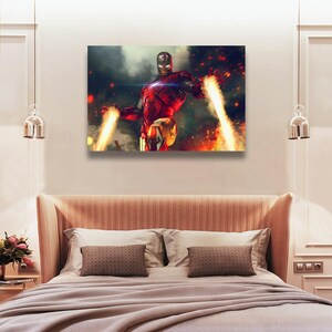 May include: A canvas print featuring Iron Man in a dynamic pose, with his hands emitting bright yellow energy beams. The artwork showcases a red and gold armored figure against a backdrop of fiery explosions and a smoky atmosphere.