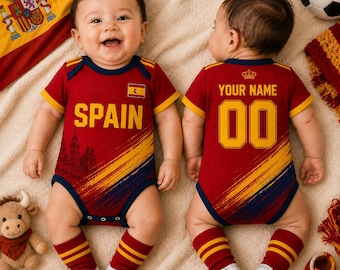 Könnte beinhalten: Ein roter Babybody mit gelben und blauen diagonalen Pinselstrich-Akzenten. Die Vorderseite zeigt den Text SPAIN und eine kleine spanische Flagge. Die Rückseite zeigt den Text YOUR NAME und die Nummer 00 in Gelb sowie ein kleines Kronensymbol.
