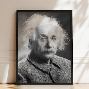 May include: A black and white portrait of Albert Einstein in a thin black frame. The image shows a close-up of Einstein with his signature wild hair and mustache, wearing a textured tweed-style jacket. The portrait is captured in a classic style.