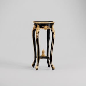 May include: A small, ornate black side table with gold accents. The table has a round top and curved legs, with decorative gold detailing along the edges and legs. A small, decorative piece is at the base of the legs.
