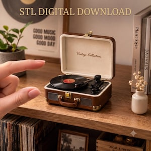 May include: A brown suitcase-style record player with a black turntable, a tonearm, and a cream-coloured interior lid featuring the text Vintage Collection. The exterior has gold-tone metal latches, corner protectors, and a handle.