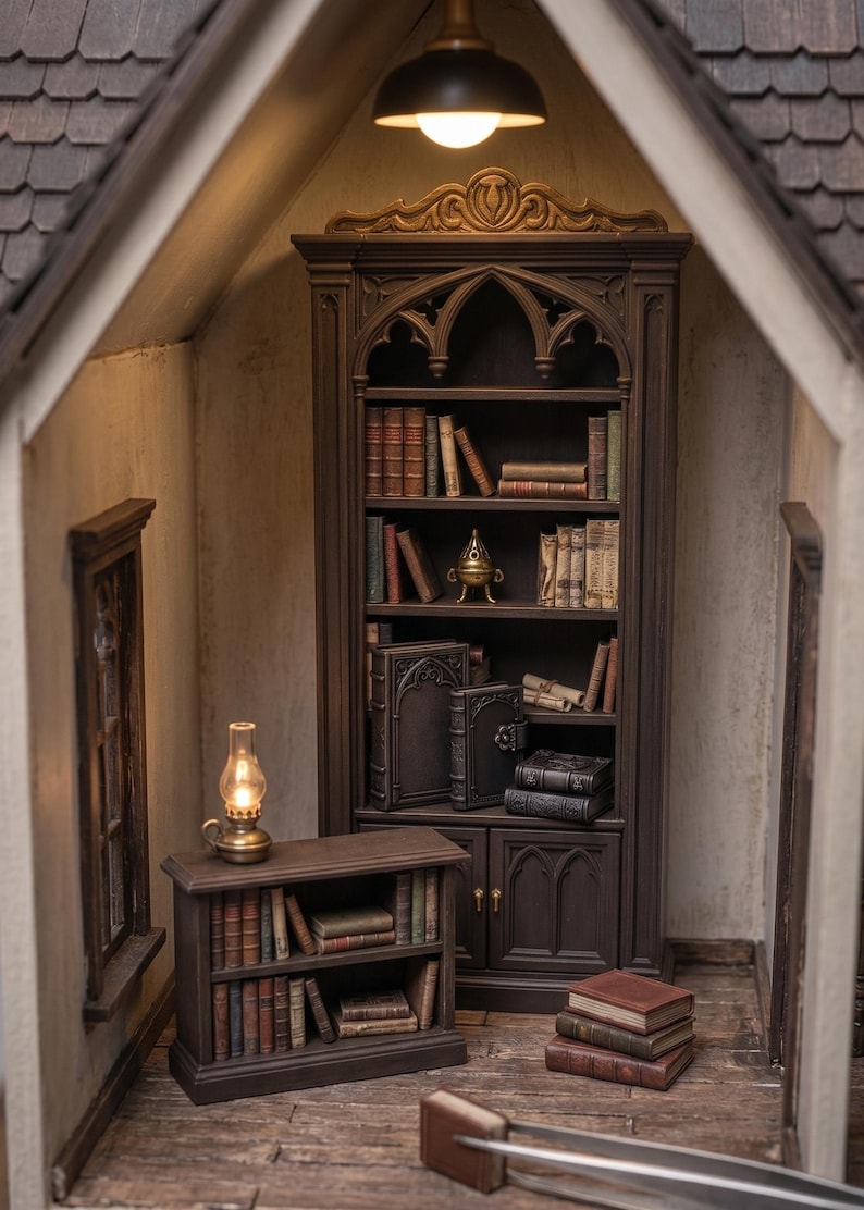 May include: Miniature library scene with a large dark brown bookcase filled with books. A small table with books and a lamp sits in front of the bookcase. The scene is lit by a hanging light and a small oil lamp.