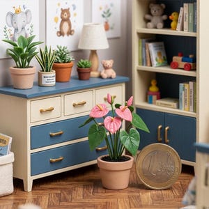 May include: A miniature bedroom scene with a blue and cream-colored dresser, adorned with potted plants and framed artwork. A one Euro coin is next to a potted anthurium plant with pink flowers. A bookshelf is in the background.