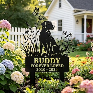 Puede incluir: Estaca de jardín de metal negro con la silueta de un perro Labrador Retriever, flores y una mariposa. La estaca dice "BUDDY FOREVER LOVED 2010-2024". La estaca está colocada en un jardín con flores coloridas.