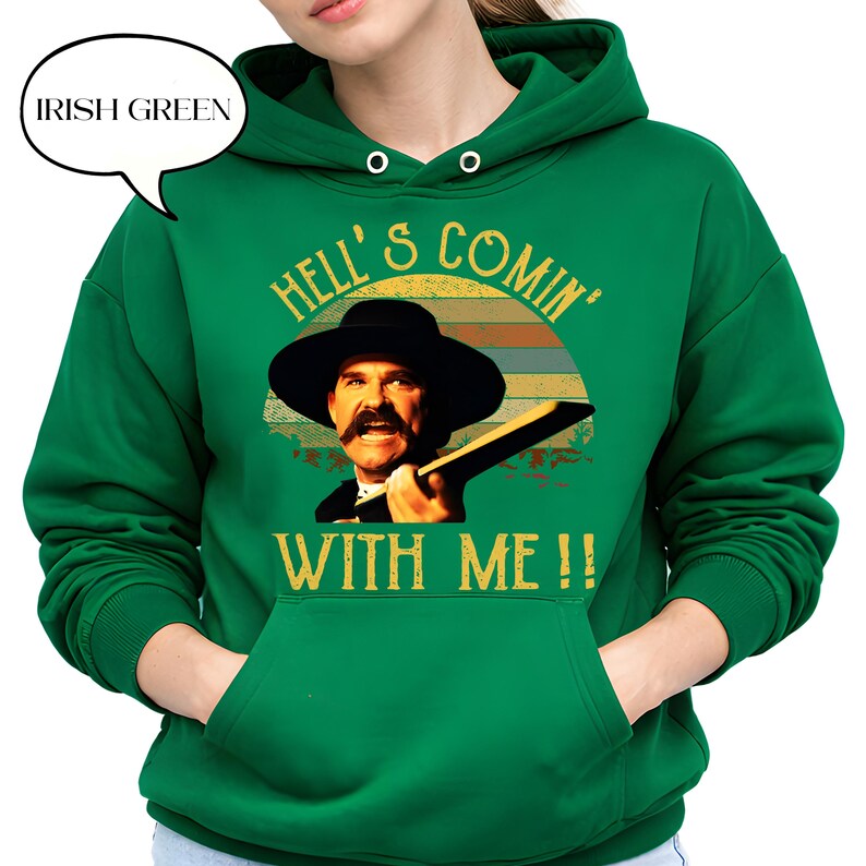 May include: An Irish green hooded sweatshirt featuring a graphic print of a man in a wide-brimmed hat with a mustache. The text reads HELL'S COMIN' WITH ME!! above and below the image, set against a retro-style sunset background design.