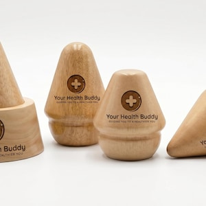 May include: Four light-colored wooden massage tools of varying shapes and sizes. Each piece features a circular logo with a plus sign and the text Your Health Buddy, Guiding You to a Healthier You. The items have a smooth, polished finish.