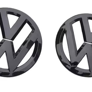 Puede incluir: Dos emblemas Volkswagen negros brillantes. Cada emblema presenta el icónico logotipo de VW, una 'V' y una 'W' estilizadas dentro de un círculo. Los emblemas son circulares y tienen una superficie reflectante y brillante, lo que sugiere un accesorio para automóvil.
