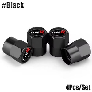 May include: Four black tyre valve stem caps. Each cap features the text "TYPE R" in white with a red "R" on a black background. The caps are hexagonal in shape.