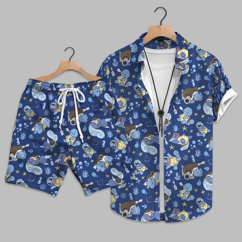 K&ouml;nnte beinhalten: Ein Set aus einem kurz&auml;rmeligen Hemd mit Knopfleiste und passender Shorts in Dunkelblau, mit einem durchgehenden Muster aus hellblauen Schildkr&ouml;tenfiguren, gelben Sternen und kleinen maritimen Elementen &uuml;ber einem wei&szlig;en T-Shirt.